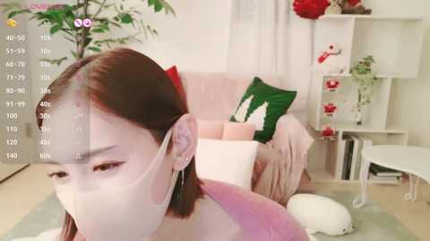 Media: Video of a young East Asian woman with fair skin and straight, shoulder-length brown hair, wearing a pink top, lying on a white couch in a modern living room.