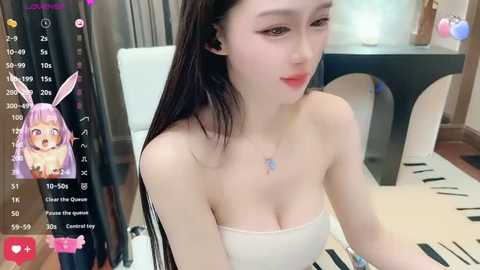 Media: Video of a young, fair-skinned woman with long black hair and bunny ears, wearing a strapless white top. She's sitting at a table with a mirror in the background, reflecting a room with a white chair.