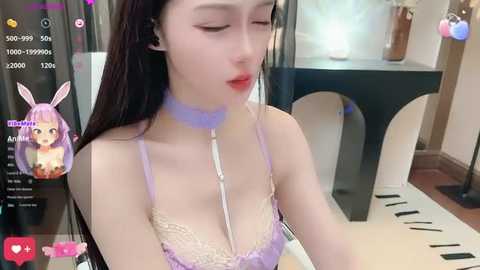 Media: A video of an Asian woman with fair skin, long black hair, and purple bunny ears, wearing a lavender lace bra and choker, sitting indoors, with a digital filter overlay.