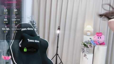 Media: Video of a gamer's setup: a black gaming chair with \"just a pillow\" text, a pink Kirby plush, a lamp, and a monitor displaying game stats.