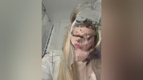 Media: A video of a woman with long blonde hair and pale skin, partially covered by a plastic bag, in a dimly lit room with white walls and a bed.