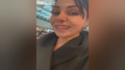 Media: A video of a smiling Latina woman with dark hair, wearing a black robe, taken indoors, possibly in a hospital setting.