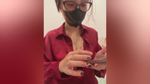 Media: Video of a woman in a red blouse, black mask, and glasses, applying lipstick to a man's penis, with blurred red background.