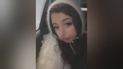 A video shows a young woman with long dark hair, wearing a fluffy white and black costume, pouting and blowing a bubble.