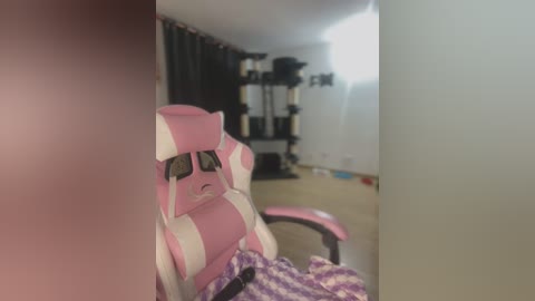 Media: Video of a pink and white gaming chair with a distressed face expression, set in a dimly lit, minimalist room with a treadmill in the background.