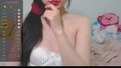 Media: A video of a young Asian woman with fair skin, long black hair, and red lipstick. She's wearing a white lace bra, and the background features a pink teddy bear.