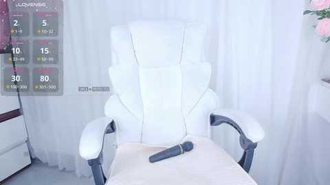 Media: Video of a modern, white leather massage chair with adjustable headrest and armrests, positioned in a softly lit, minimalist room with white curtains and a digital display panel showing treatment options.