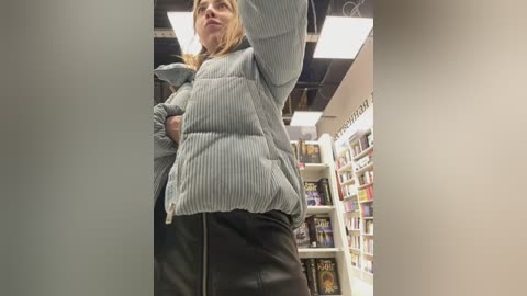 Media: Video of a woman in a pinstriped jacket and black leather skirt standing in a brightly lit bookstore with shelves full of books.