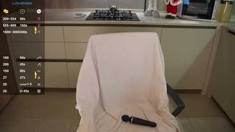 Media: A video of a modern kitchen showing a white towel draped over a chair, a black microphone on the seat, and a stove in the background.