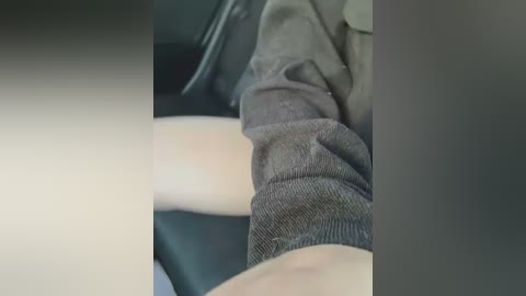 Media: Video of a close-up view of a person's leg, showing the lower thigh and calf in a grey, ribbed sock. The background is blurred, with a focus on the texture and color of the sock.