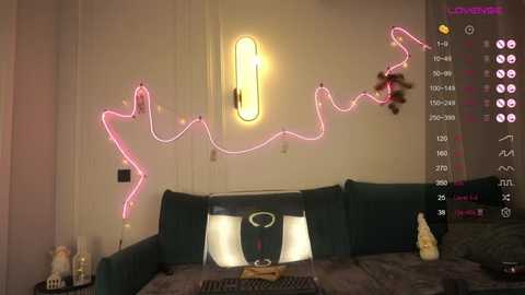 Media: Video of a cozy living room with a dark green couch, neon pink wireframe heart decor, soft lighting, and a laptop on the coffee table.