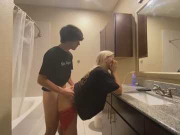 Media: Video of a young man in a black shirt, penetrating a woman in a black dress in a bathroom with beige walls and a white bathtub.