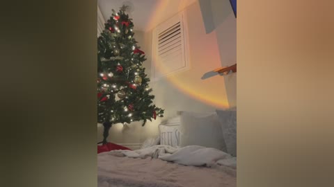 Video of a cozy, dimly-lit bedroom with a decorated Christmas tree and a bed covered in white blankets, creating a warm, festive ambiance.