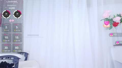 Media: Video of a modern, minimalist room with white curtains, a pink floral arrangement, and a digital display showing weather and temperature information on the left.