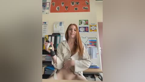 Media: Video of a red-haired, white woman in a white lab coat, smiling, holding a syringe in a cluttered classroom with colorful posters and bookshelves.