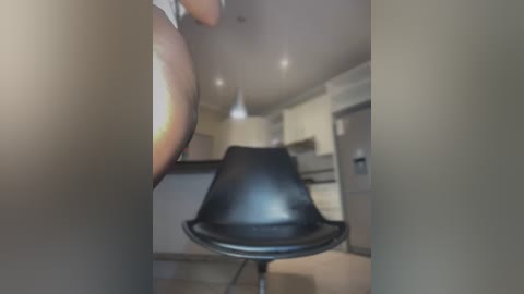 Media: Video of a modern kitchen with a sleek black chair, white cabinets, and a soft lighting ambiance. The image is slightly blurred, creating a dreamy, ethereal atmosphere.