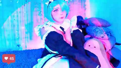 Media: Video of a woman in a maid outfit with blue hair, sitting on a plush toy in a pink and blue room, with a heart icon and 45 likes in the corner.