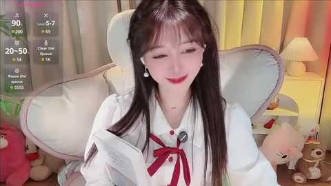 Media: Video of a young Asian woman with long black hair, fair skin, and red lipstick, smiling while reading a book in a cozy room with plush toys and a lamp.