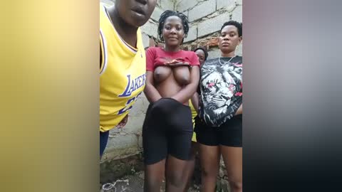 Media: Video of three Black women standing in an urban setting, with one woman lifting her red shirt to expose her breasts.