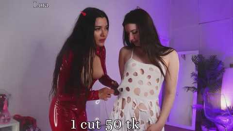 Media: Video of two women in provocative outfits: one in a red latex dress, the other in a white polka-dotted one. Background includes purple lighting and potted plants.