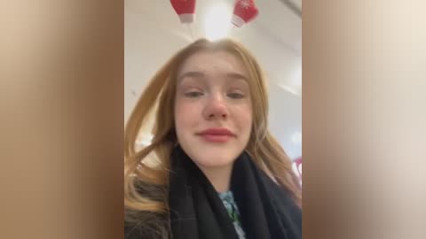 Media: Video of a young woman with fair skin and long blonde hair, wearing bunny ears and a black coat, indoors with blurred background.