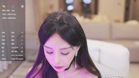 Media: Video of an East Asian woman with long, straight black hair, wearing a strapless dress, standing in a modern, well-lit room. She has fair skin and is looking down.