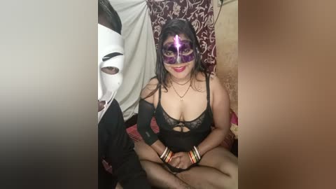 Media: A video of a woman in a revealing black lace lingerie and purple mask, sitting on a bed with a man in a white mask.