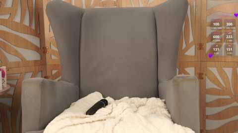 Media: Video of a modern hospital bed with a plush, grey, high-backed headboard and white, soft bedding. The background features a wooden screen with a leafy pattern and a digital display panel showing vital signs.