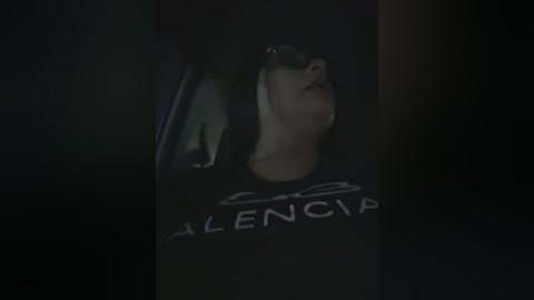 Media: Video of a person in a dark room, wearing black sunglasses and a black \"ALLENCAVE\" t-shirt, looking up with a contemplative expression.