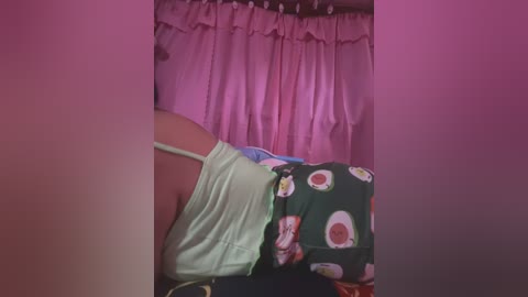 Media: A video of a person lying on a bed with a green shirt and a green and white bedspread featuring sushi patterns, surrounded by pink curtains.