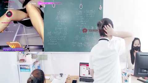 Media: Video of an Asian woman with dark hair, wearing a white shirt, scratching her head while standing in front of a green chalkboard filled with mathematical equations. A young Asian girl in a white dress sits on a stool, watching.