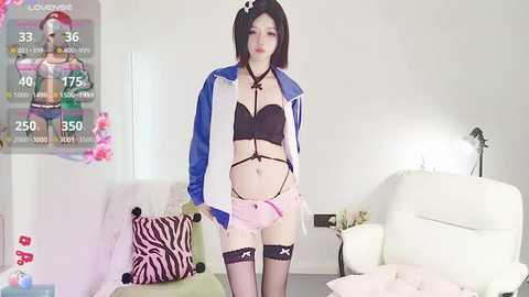 Media: A video of an Asian woman with fair skin, short black hair, wearing a blue jacket, black bra, pink garter belt, and shorts, standing in a modern living room with white furniture and floral accents.