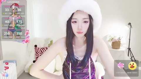 Media: Video of a young, slender Asian woman with long black hair wearing a white furry hat and a purple sequined top, posing in a brightly lit bedroom with zebra-print pillows and a lamp.