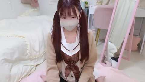 Media: Video of an Asian woman in a school uniform, with a white mask covering her face, sitting on the floor in a bright, neatly organized room with white walls and pastel furniture.