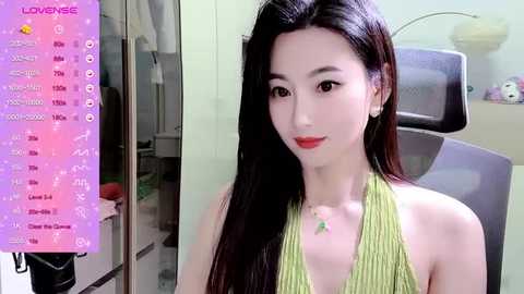 Media: A video of an East Asian woman with long, straight black hair and fair skin, wearing a green halter top, sitting indoors in a modern office setting. The image is overlaid with a \"Lomondise\" app interface.