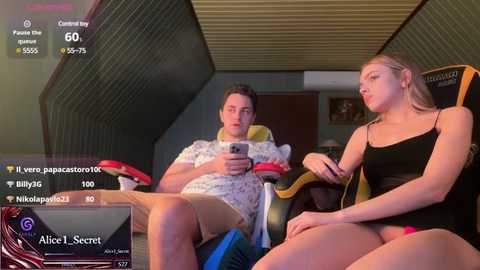 Media: A video of two young people sitting on a couch, watching a video game. The woman, wearing a black dress, looks concerned. The man, in a white shirt, holds a controller.