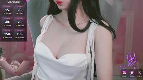 Video of a fair-skinned woman with long black hair, wearing a white, strapless dress, sitting indoors. Digital display in the background shows statistics like 15 viewers, 40% of viewers like her, and 70% of viewers are female.