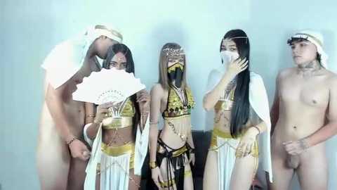 Media: Video of four nude Asian men and a partially nude woman in Egyptian-themed costumes, holding fans, in a white room.