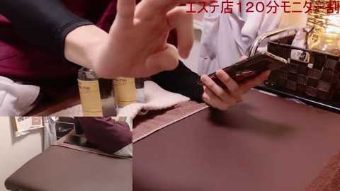 Media: Video of a person with fair skin, wearing a black long-sleeved shirt and maroon sweater, using a smartphone while holding a chocolate bar. Background shows a marble countertop and a brown basket filled with groceries.