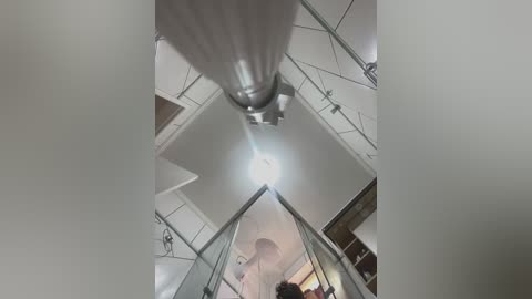 Media: A video taken from a high vantage point shows a modern building's interior with a central, bright, circular skylight, surrounded by glass panels and steel beams. The scene is illuminated by natural light.