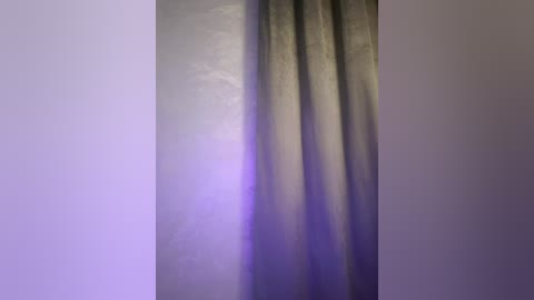 Media: A video of a tall, vertical curtain with a smooth, slightly shiny texture. The background is a soft, gradient mix of purple and lavender hues. The curtain's color transitions from light beige at the top to a darker grayish tone at the bottom.