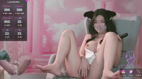 Media: A digital video featuring an Asian woman with black cat ears, topless, and sexually explicit pose in a pastel-themed room.