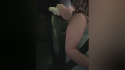 Media: Video of a woman in a car, seen from behind, wearing a white sock on her right foot. Her dark brown hair is partially visible.