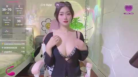 Media: Video of an East Asian woman with fair skin, dark hair, wearing a black sheer robe, exposing a black lace bra, in a modern room with a digital display and green decor.