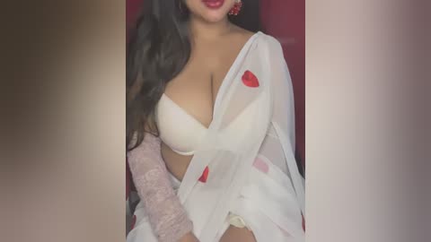 Media: Video of a woman with long, dark hair, wearing a white, sheer, red heart-patterned robe and a light pink bra, against a red background.