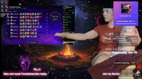 Media: Video of a live streamer in a brown t-shirt and skirt, holding a controller, with a virtual campfire and digital overlay of chat messages.