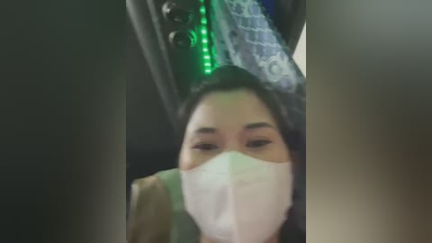 Media: Video of an East Asian woman in a car, wearing a face mask, green headband, and dark hair, with blurred background.