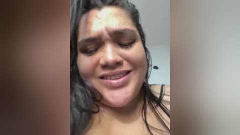 Media: Video of a smiling, wet-haired Latina woman with medium skin tone, wearing a strapless top, in an indoor setting.