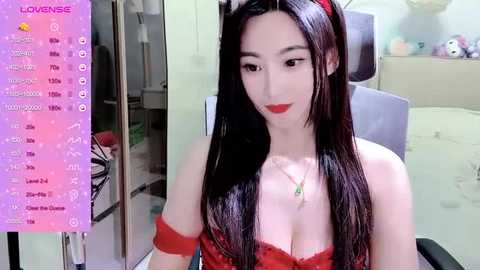 Media: Video of an Asian woman with long black hair, wearing red lingerie and a red headband, in a bedroom with a bed, wardrobe, and plush toys.