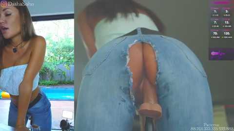 Media: Video: A young woman with light brown skin and long brown hair, wearing a strapless white top and distressed blue jeans, leans over a poolside table.